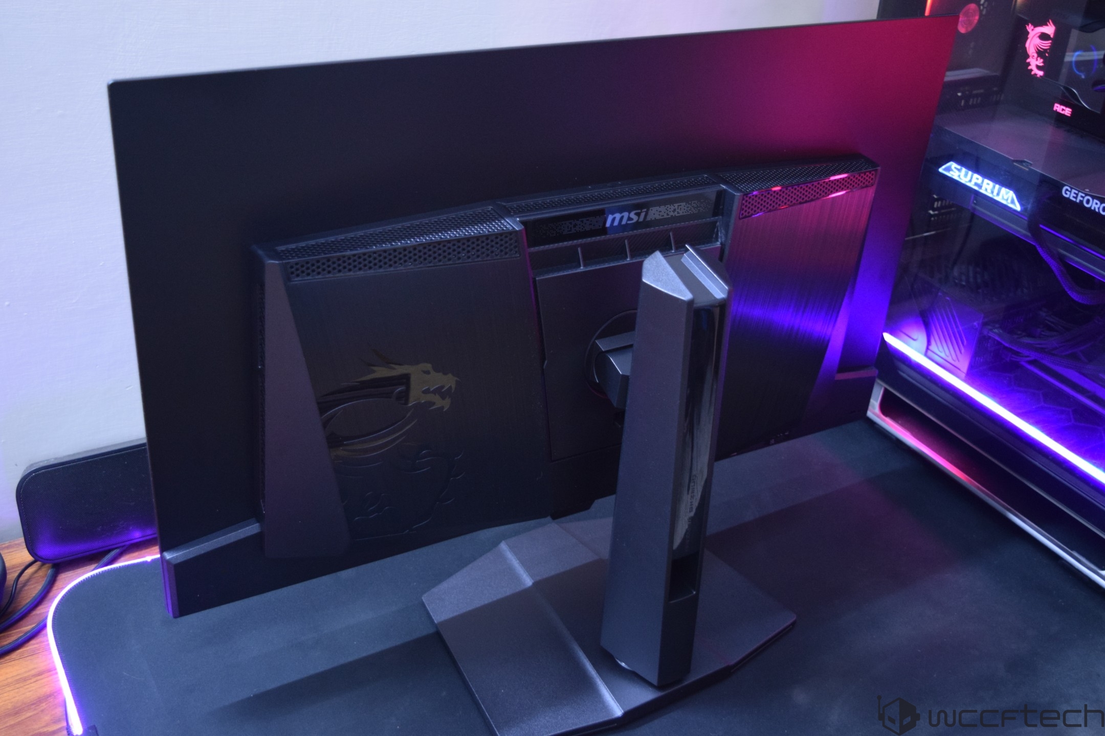The back view of an MSI Optix MAG monitor displaying the MSI logo and dragon emblem, next to a computer case labeled 'SUPRIM GeForce RTX.'