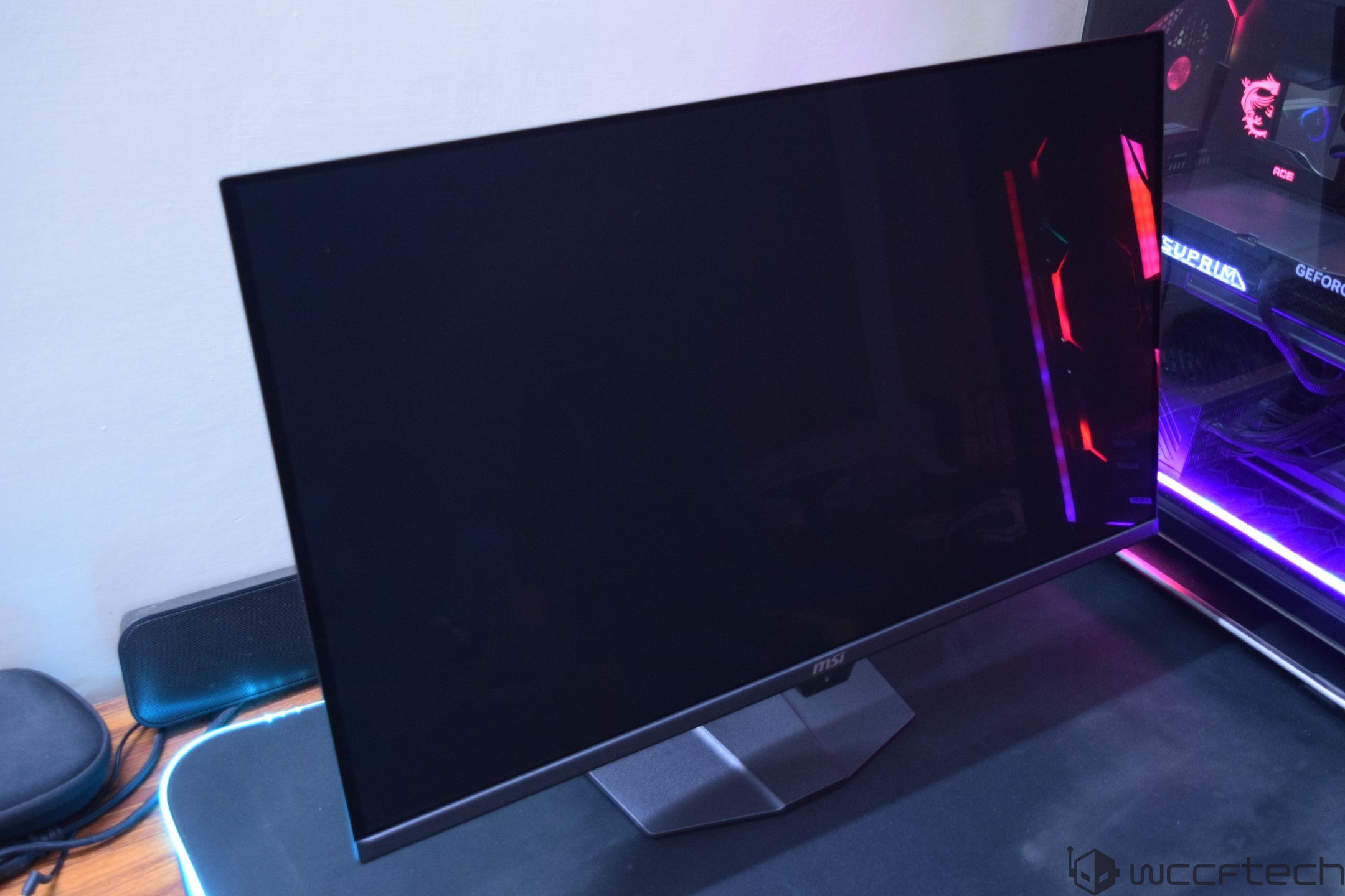 An MSI monitor with a blank screen is placed next to a gaming PC with visible RGB lighting.