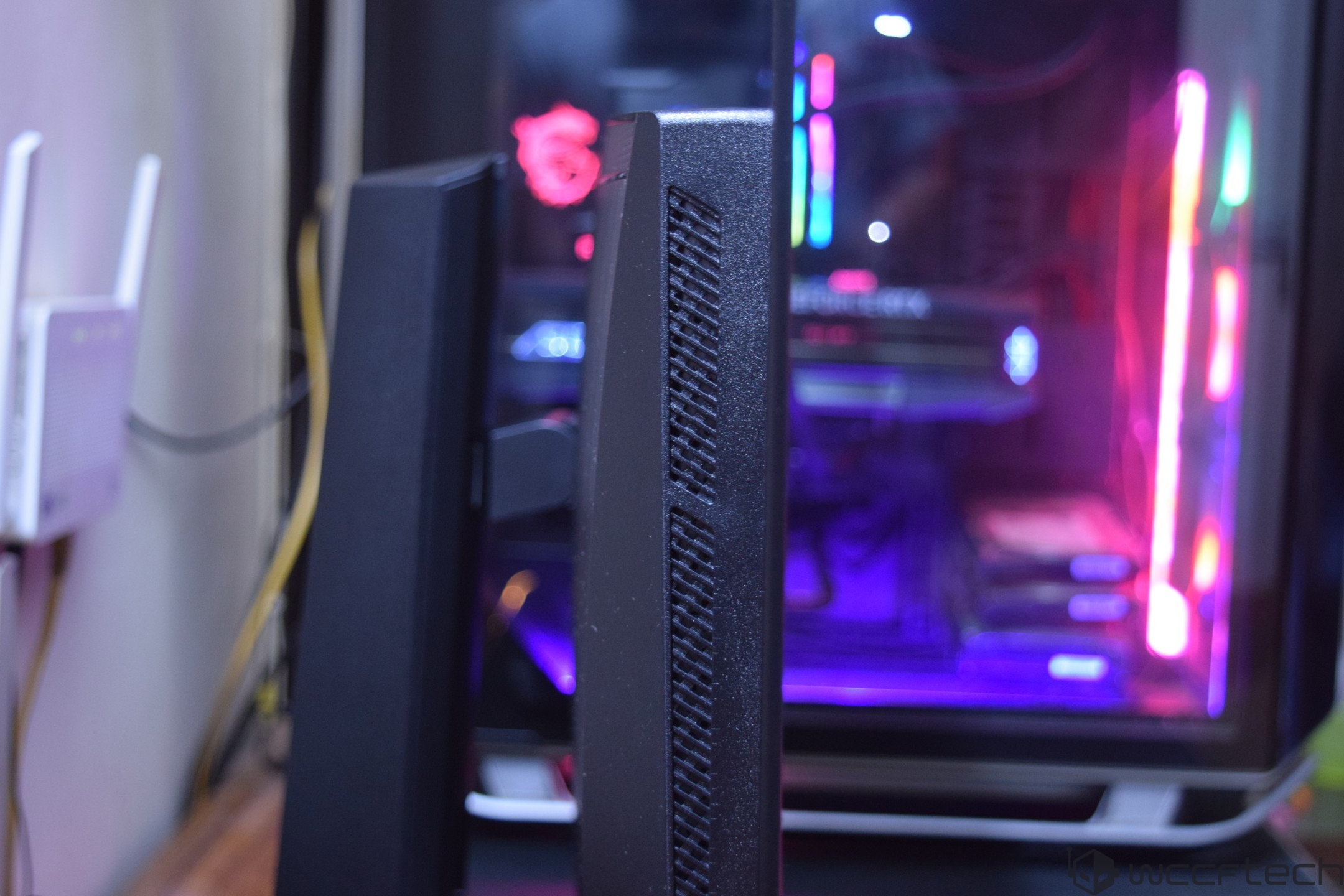 A side view of a desktop monitor with a visible MSI logo in the background, showing colorful RGB lighting inside a gaming PC case.