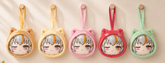 Five plush keychains with winking cartoon faces and animal ear hoods in yellow, orange, pink, red, and green hang in a row.