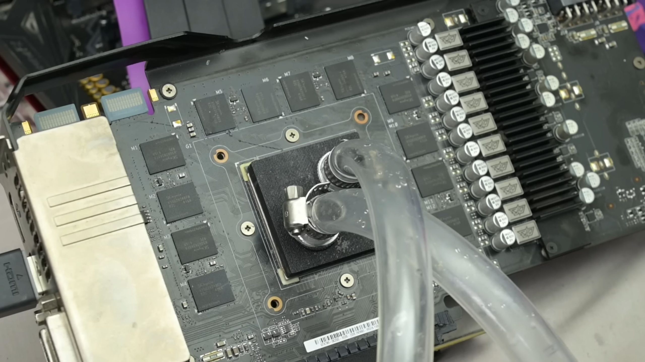 A disassembled GPU with visible circuitry and cooling pipes attached to the core area.
