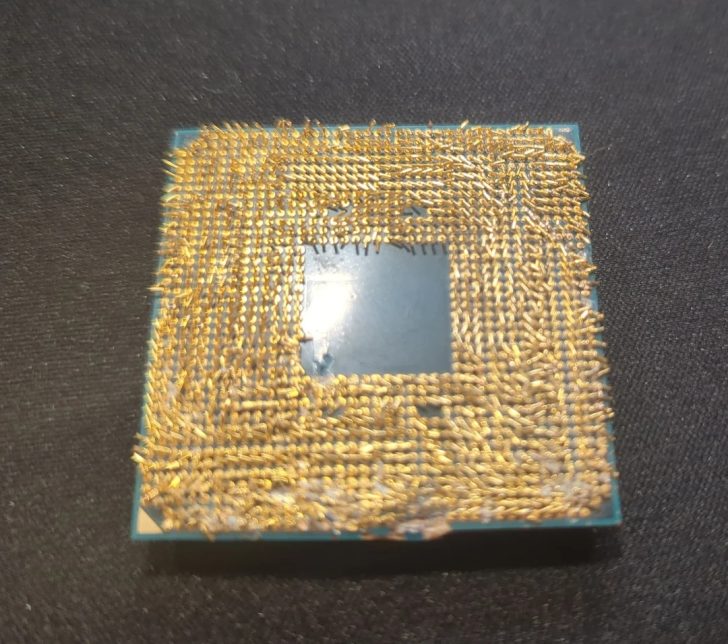 An Intel processor with bent and damaged pins on a dark surface.
