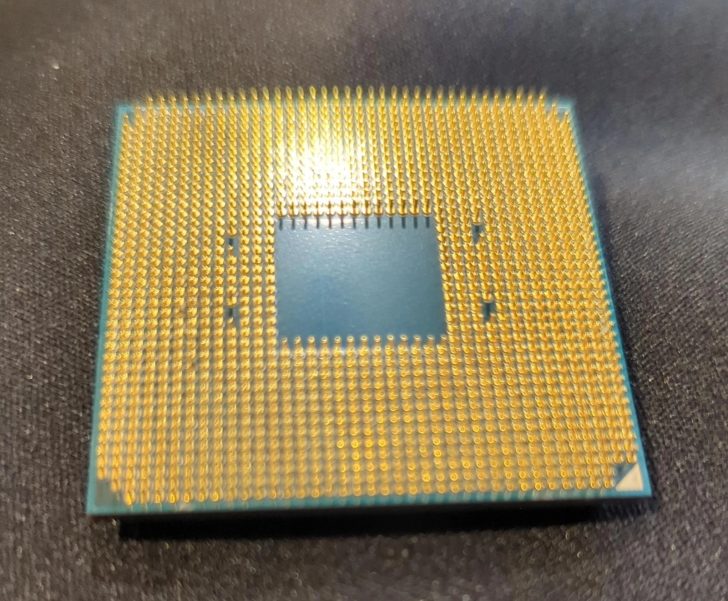 The bottom view of an unbranded CPU showing a grid of gold pins on a dark surface.