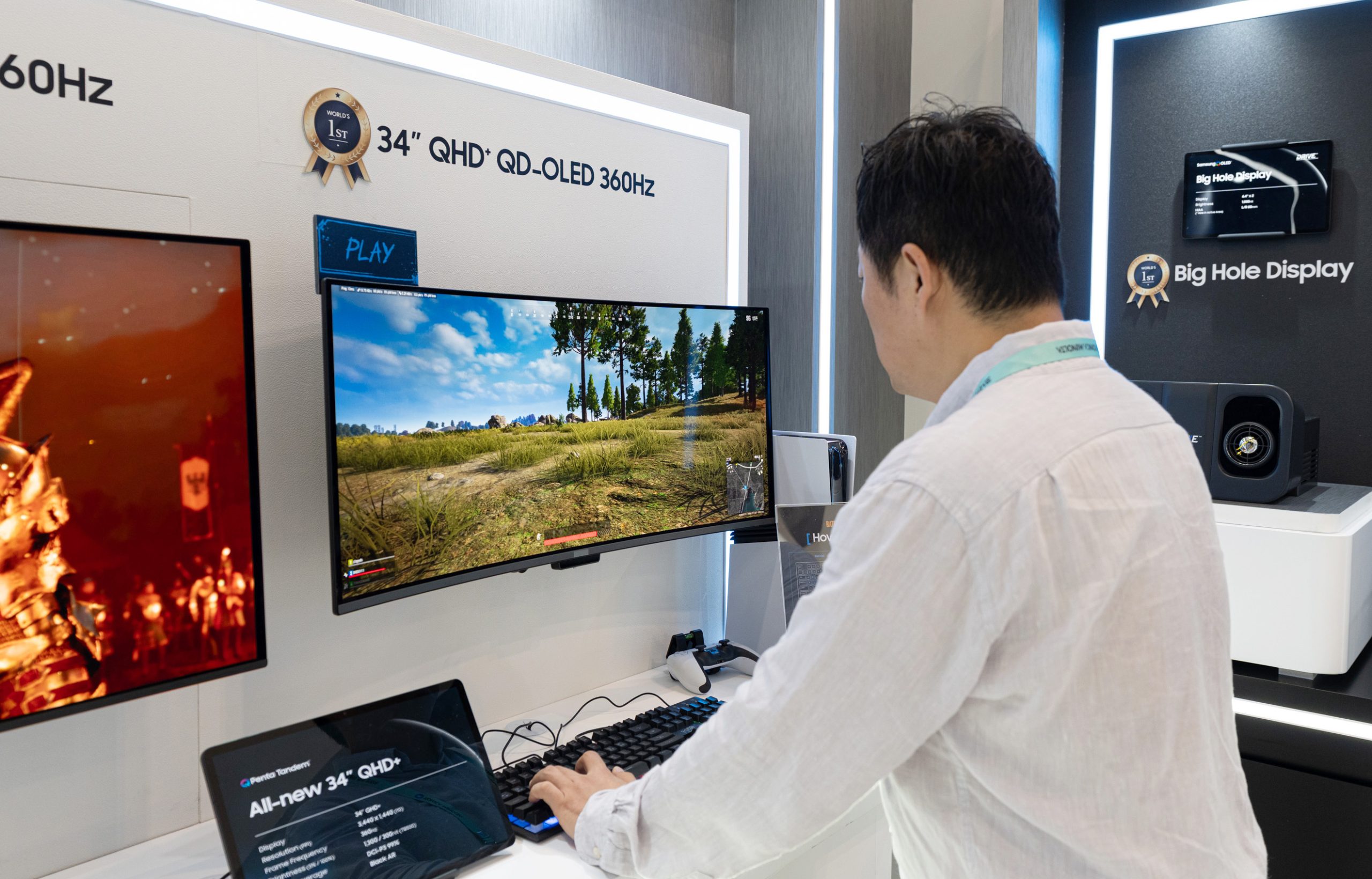 A person using a 34 QHD+ QD-OLED 360Hz monitor displaying a game, with 'All-new 34 QHD+' written on a tablet below.