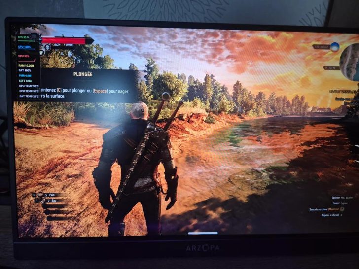 A character in The Witcher 3 stands by a river with on-screen text 'PLONGÉE' indicating dive controls on an Arzopa monitor.